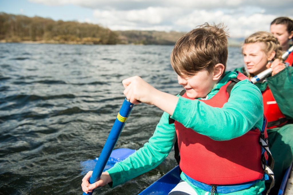 Scouts paddle on the open water in a canoe.