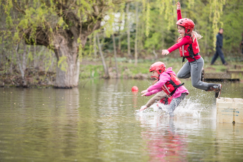 Two cubs jump into a body of water.