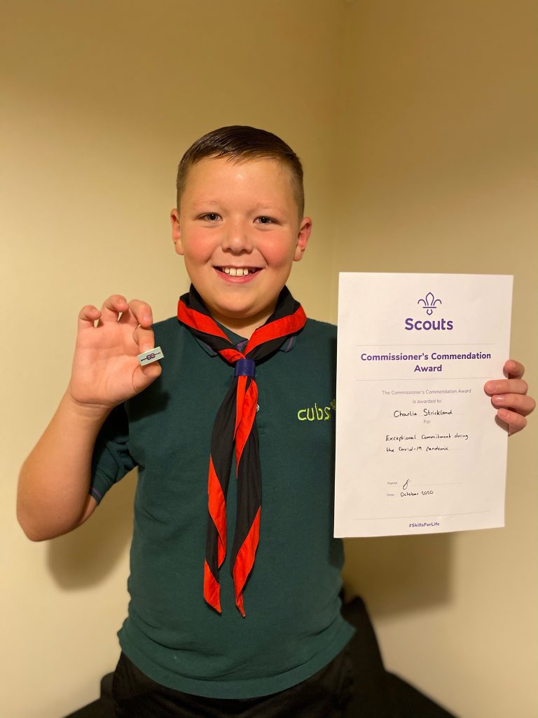 Charlie Stickland, a Cub, holding his award achieved through his cycling efforts.