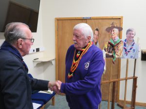 Brian Calver, a volunteer from the New Forest, receives his Bar to the Silver Acorn with pictures and props of Scouting Founder Robert Baden-Powell and Chief Scouts Bear Grylls and Peter Duncan in the background.