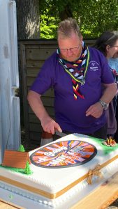 Kerie Wallace, Scout volunteer, cuts a cake to celebrate the 60th anniversary of a Scout group.