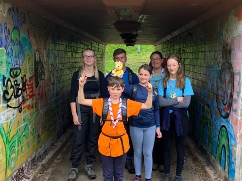 A group of six Scout young people and adult volunteers in walking gear standing in a subway in remote Scotland.