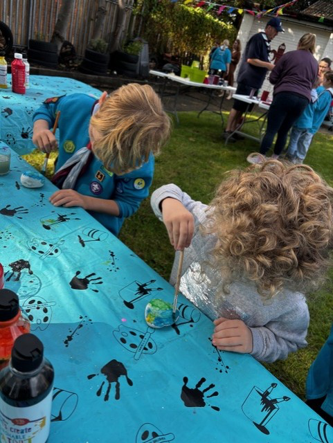 Two young people take part in craft activities to paint designs onto rocks.