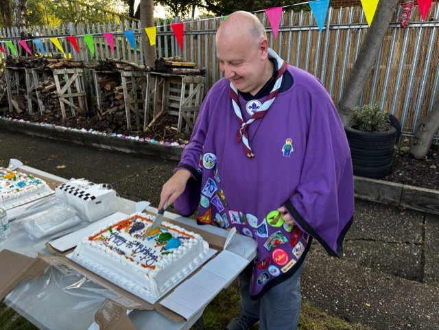 A volunteer cuts the birthday cake for the group.